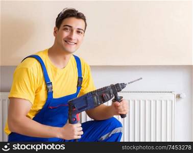 Young repairman contractor repairing heating panel