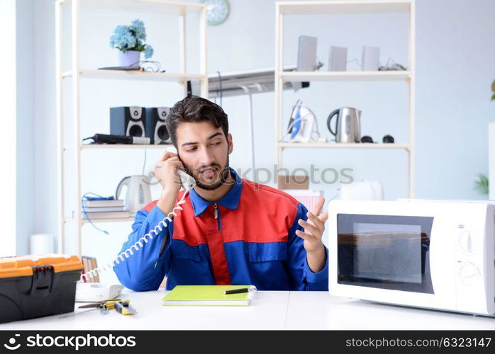 Young repairman fixing and repairing microwave oven