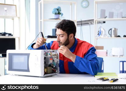 Young repairman fixing and repairing microwave oven