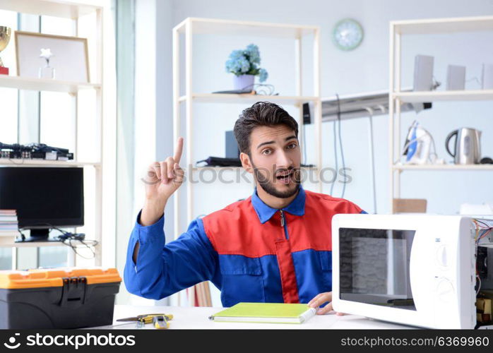 Young repairman fixing and repairing microwave oven