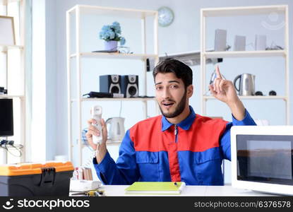 Young repairman fixing and repairing microwave oven