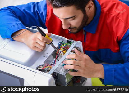 Young repairman fixing and repairing microwave oven