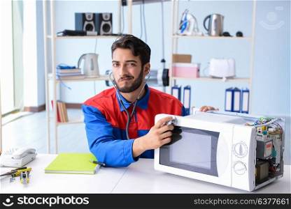 Young repairman fixing and repairing microwave oven