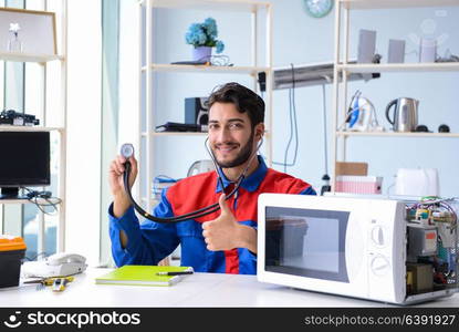 Young repairman fixing and repairing microwave oven