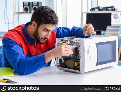 Young repairman fixing and repairing microwave oven. The young repairman fixing and repairing microwave oven