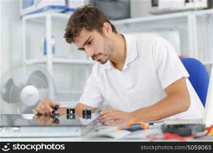 young repairman installing induction cooker in kitchen