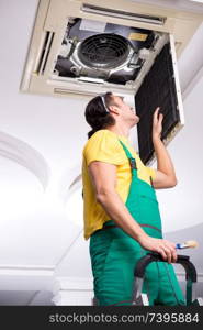 Young repairman repairing ceiling air conditioning unit 