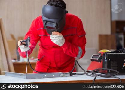Young repairman with a welding gun electrode and a helmet weldin. Young repairman with a welding gun electrode and a helmet welding metal
