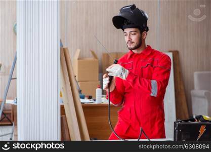 Young repairman with a welding gun electrode and a helmet weldin. Young repairman with a welding gun electrode and a helmet welding metal