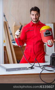 Young repairman with a welding gun electrode and a helmet weldin. Young repairman with a welding gun electrode and a helmet welding metal