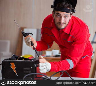 Young repairman with a welding gun electrode and a helmet welding metal. Young repairman with a welding gun electrode and a helmet weldin