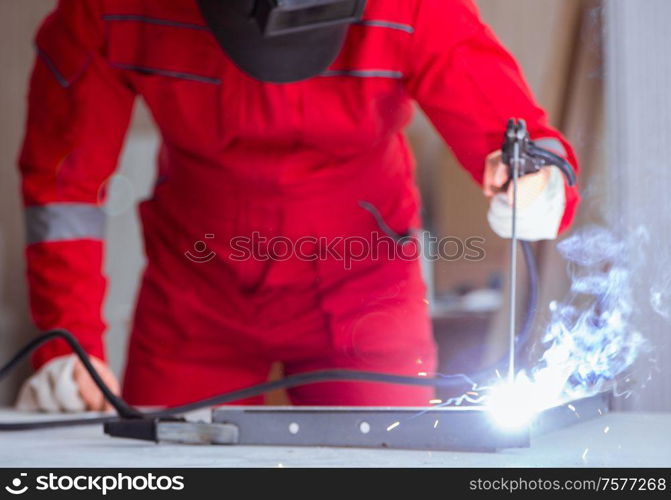 Young repairman with a welding gun electrode and a helmet welding metal. Young repairman with a welding gun electrode and a helmet weldin