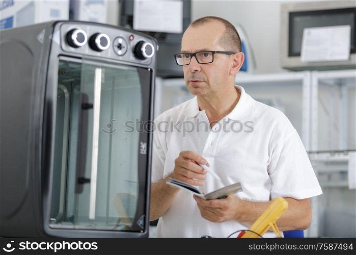 young repairman with screwdriver fixing kitchen oven