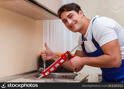 Young repairman working at the kitchen