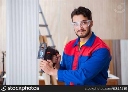 Young repairman working with a power saw sawing
