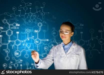 Young researcher. Young woman researcher in medical uniform drawing chemistry formulas