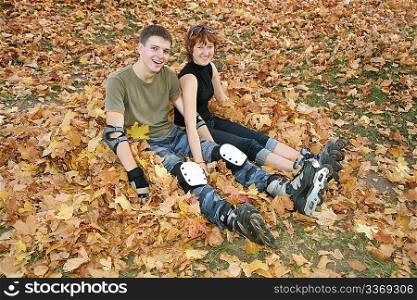 young roller couple sit on yellow leaves