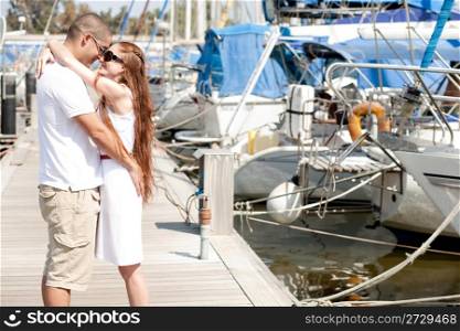 Young romantic couple hugging and standing at the harbour