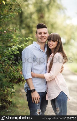 Young romantic couple is having fun in summer sunny day in park. Enjoying spending time together in holiday. Man and woman are hugging and smiling. Young romantic couple is having fun in summer sunny day in park. Enjoying spending time together in holiday. Man and woman are hugging and smiling.