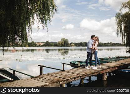 Young romantic couple is having fun in summer sunny day near the lake. Enjoying spending time together in holiday. Man and woman are hugging and kissing. Young romantic couple is having fun in summer sunny day near the lake. Enjoying spending time together in holiday. Man and woman are hugging and kissing.