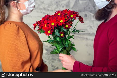 Young romantic loving male wearing a protective face mask for coronavirus and give young female a bouquet of flowers, Covid-19, Valentines Day, Birthday concept romance. Young romantic loving male wearing a protective face mask for coronavirus and give young female a bouquet of flowers, Covid-19, Valentines Day, Birthday concept