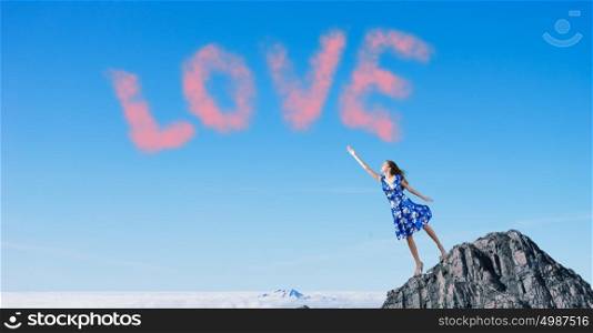 Young romantic woman in summer dress reaching word love. Love and romance