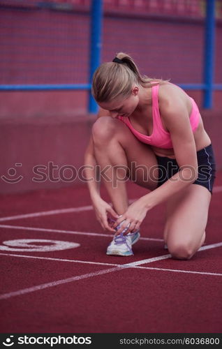 young runner sporty woman relaxing and stretching on athletic race track