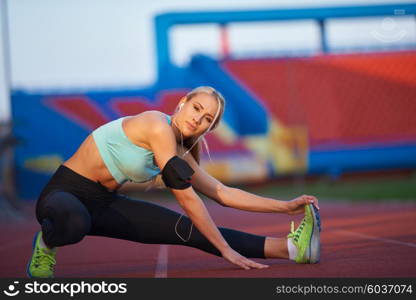 young runner sporty woman relaxing and stretching on athletic race track