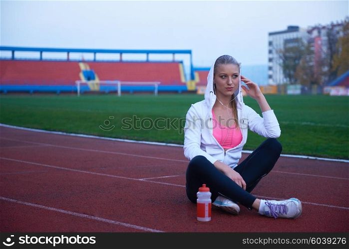 young runner sporty woman relaxing and stretching on athletic race track
