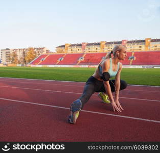 young runner sporty woman relaxing and stretching on athletic race track