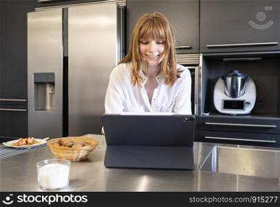 young Russian woman looking at laptop computer in a kitchen