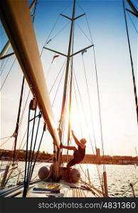 Young sailor working on sailboat, pulling rope, sailing sport, active lifestyle, captain on the ship, bright sunset light, summer adventure, travel concept