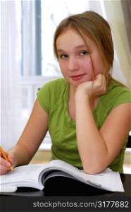 Young school girl doing homework at her desk