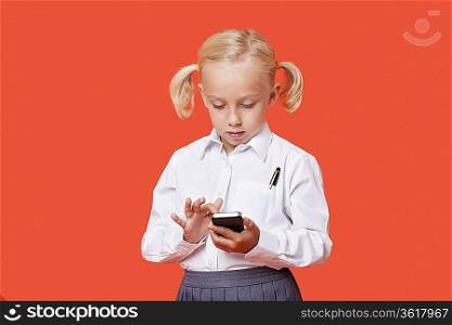 Young school girl reading text messages over orange background