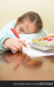 Young schoolgirl falling asleep while doing her homwork