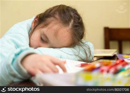 Young schoolgirl falling asleep while doing her homwork