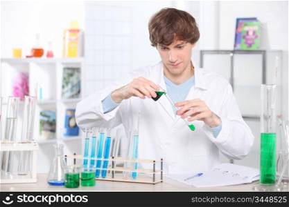 young scientist in a laboratory is pouring some compound in a test tube
