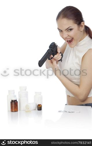Young screaming woman holding a black gun and shooting to the group of pill bottles