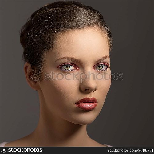 young sensual lady with purple make-up, perfect skin, brown hair looking in camera on gray background
