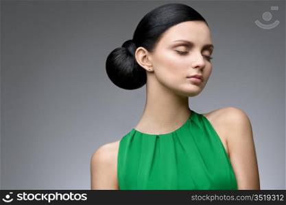young serene woman in green dress, studio shot