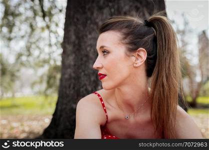Young serious blond woman with red long dress an a pigtail