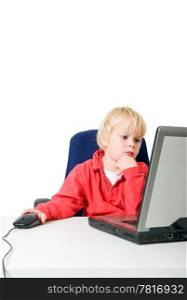Young, seriously looking, blond boy, behind a laptop, using a computer mouse