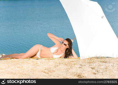 Young sexy bikini model relaxing with sunglasses on beach copyspace