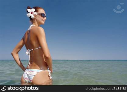 young sexy brunette in white bikini sunbathing at sea shore