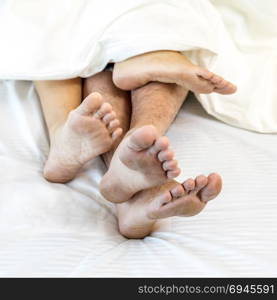 young sexy couples in love lying in bed in hotel, embracing on white sheets, close up legs, romantic mood