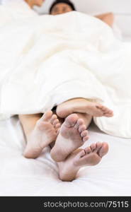 young sexy couples in love lying in bed in hotel, embracing on white sheets, close up legs, romantic mood