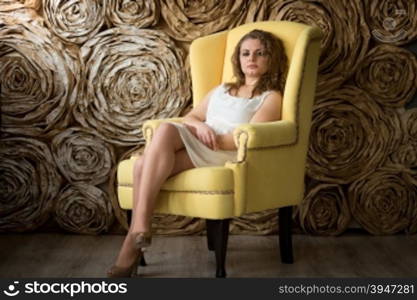 Young sexy curly woman posing in bug yellow armchair