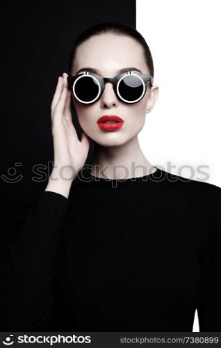 young sexy lady with black stylish sunglasses in black-and-white studio. beautiful woman with perfect lips and red lipstick pose in photostudio. Fashion portrait of fashionable model.