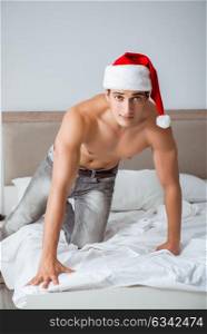 Young sexy man wearing santa hat in bed