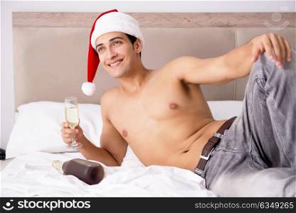 Young sexy man wearing santa hat in bed